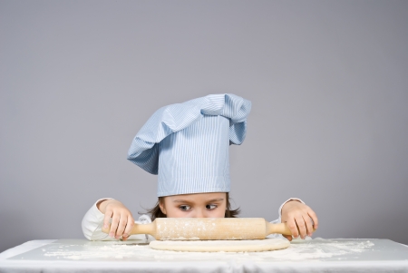Beautiful little girl cooking pizza over gray backgroundの写真素材
