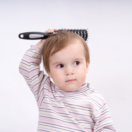 Cute little baby playing with a hairbrushの写真素材