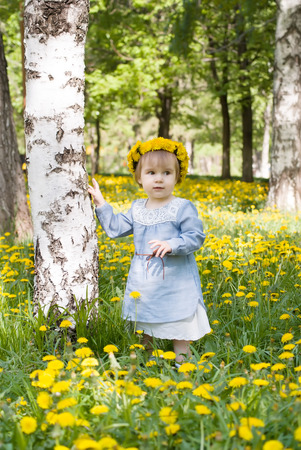 Pretty toddler girl with floral head wreath on the meadow with yellow flowersの写真素材
