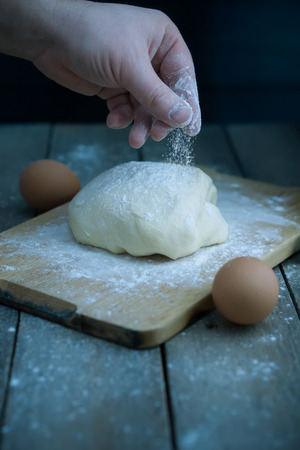 Preparing the dough. The male hand is sprinkling with flour. Early morning cooking bread.の写真素材