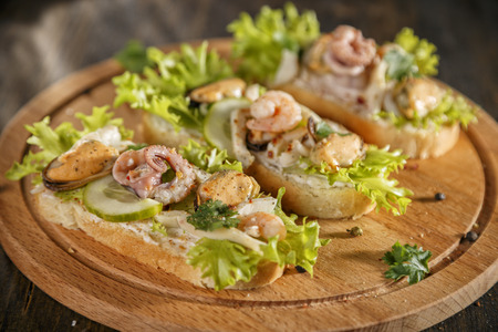 Seafood bruschetta toasted bread topped with fresh salad, parsley, cucumber, creme cheese, shrimp, octopus, musselの写真素材
