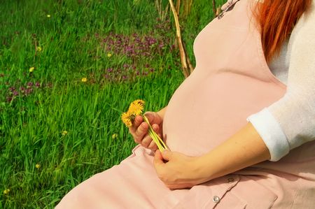 beautiful and young pregnant girl walks on spring parkの写真素材