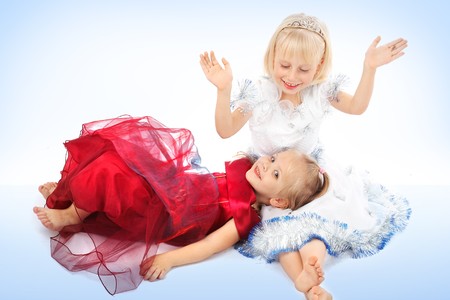 Two small girl-friends in dresses of princesses celebrate Christmasの写真素材