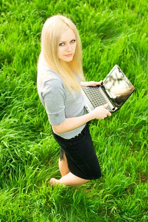 series. The beautiful business woman with the laptop has a rest in the fieldの写真素材