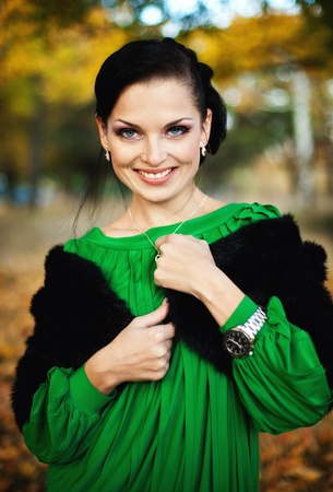 series. The beautiful brunette in a green dress walks on autumn parkの写真素材