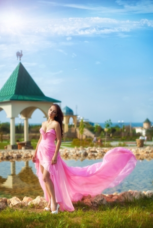 The beautiful harmonous girl in a long pink dress の写真素材