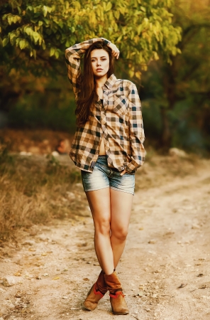 Young girl in denim shorts and a multicolored shirtの写真素材