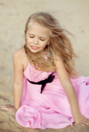 Beautiful little girl in a pink dress walkingの写真素材