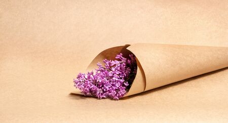 a bouquet of lilac flowers wrapped in brown craft paperの写真素材