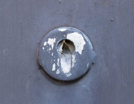 Old cracked and broken keyhole with metal doorsの写真素材
