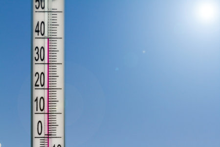 The thermometer in the heat of summer on a background of blue sky.