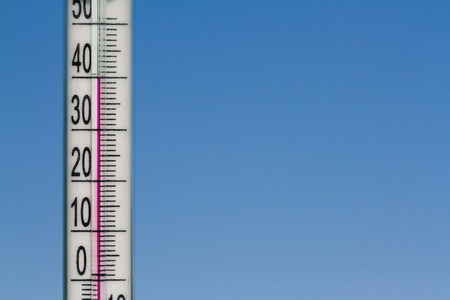 The thermometer in the heat of summer on a background of blue sky.の写真素材