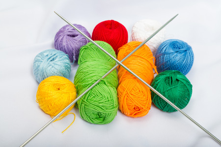 Colored balls of yarn, wool with knitting needles on white fabric.の写真素材