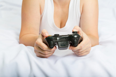 Young caucasian woman playing video game console lying on the bed