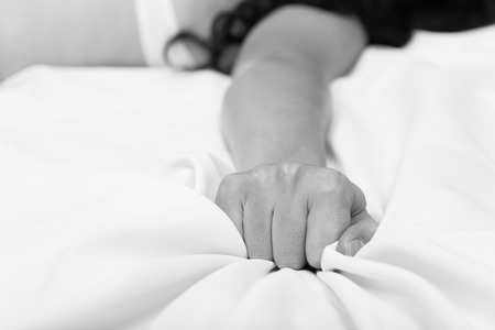 Female hand pulling white sheets in ecstasy, orgasm.の写真素材
