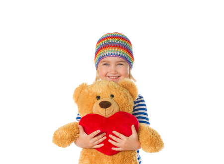 Little girl holding Teddy bear and heart. Isolated on a white background.の写真素材