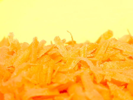 Grated carrots closeup on yellow background.の写真素材