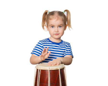 Little Funny girl in striped shirt play drum. Isolated on white background