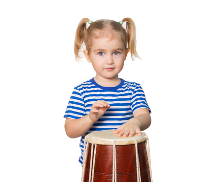 Little Funny girl in striped shirt play drum. Isolated on white backgroundの写真素材