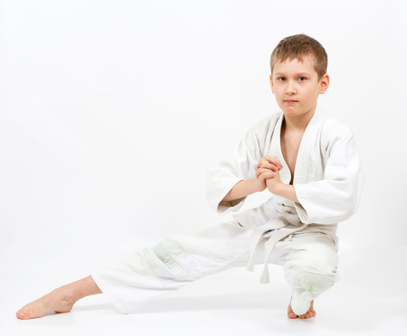 Karate boy in white kimono fighting isolated on gray backgroundの写真素材