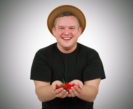 Young fat man with chili in his hands. Isolated on white background.