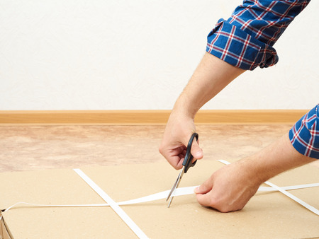 Man in a plaid shirt opens the box with furniture.の写真素材