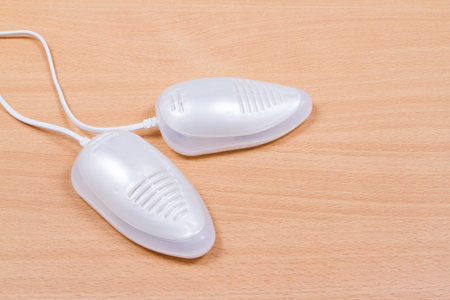 Electric ultraviolet shoe dryer isolated on wooden table.