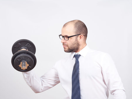 Man Trained businessman raises dumbbell. Isolated on white backgroundの写真素材