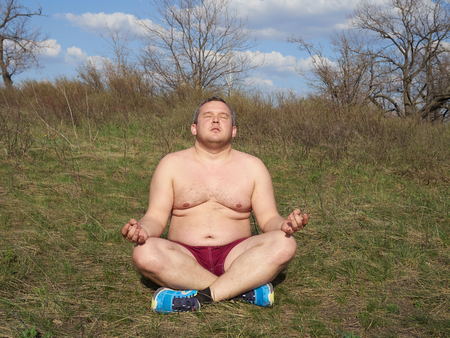 Fat man doing yoga outdoors in nature.の写真素材