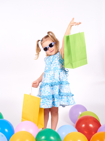 Shopping child. little girl holding shopping bags.Multi-colored balloons. Isolated on white backgroundの写真素材