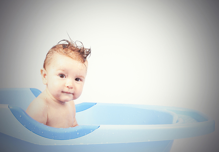 happy little babe is bathed in blue basin isolated on white backgroundの写真素材