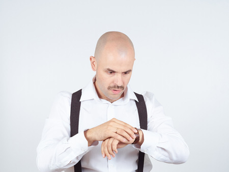 Bald businessman looks at his watch and is late.の写真素材