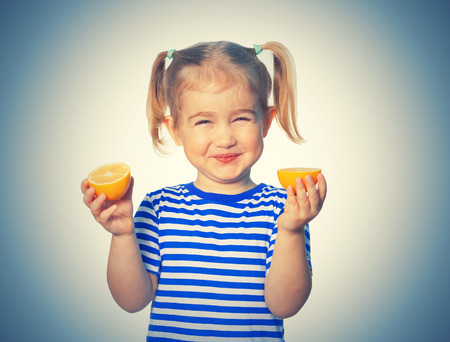 Little Funny girl in striped shirt  keeps lemons. Isolated on white backgroundの写真素材