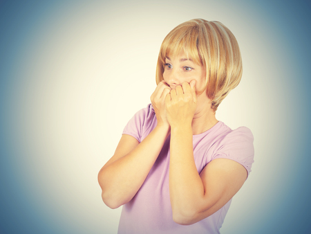Close up portrait nervous,scared, stressed young concerned woman biting fingernails looking anxiously craving something isolatedの写真素材