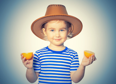 Little Funny girl in striped shirt and hat keeps lemons. Isolated on white backgroundの写真素材