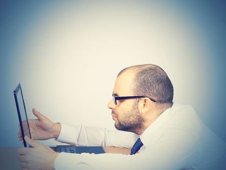 Tired businessman looking in a computer. Isolated on white backgroundの写真素材
