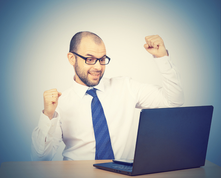 Funny photo of businessman bald with beard wearing shirt and glasses.  angry businessman working with laptop at table. Isolated on white background の写真素材