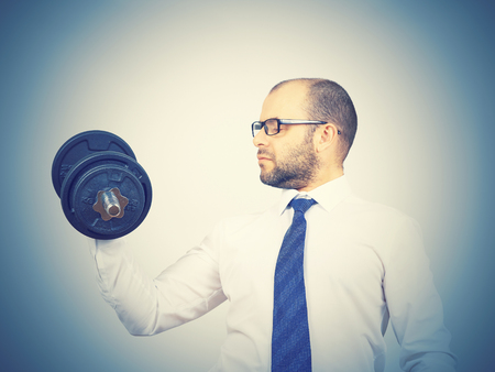 Man Trained businessman raises dumbbell. Isolated on white backgroundの写真素材