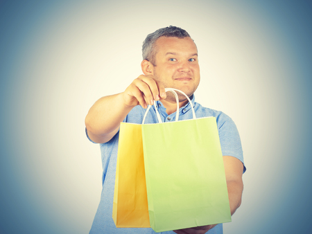 Caucasian man fat,  with colorful shopping paper bags isolated on background.   の写真素材