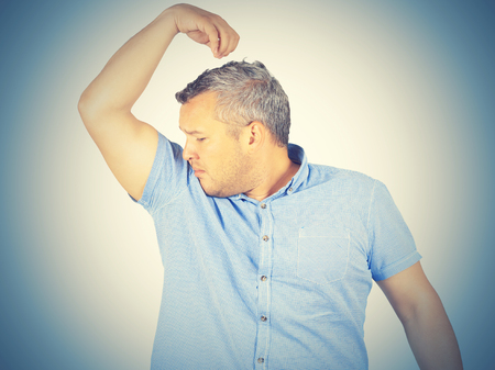 Fat man, smelling sniffing his armpit, something stinks bad, foul odor isolated on background.      の写真素材