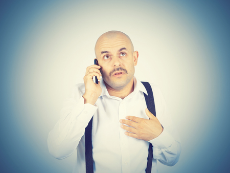 Bald mustachioed man talking on the phone. Emotions.の写真素材