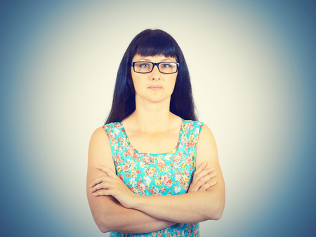 Portrait of a serious young woman with glasses and a green dress.の写真素材