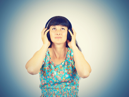 Young woman in a green dress listening to music with headphones の写真素材