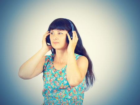 Young woman in a green dress listening to music with headphones の写真素材
