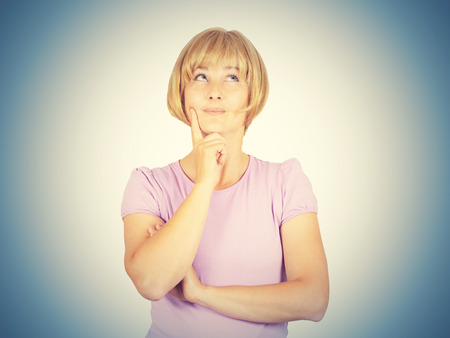 Portrait of a young Thinking  blonde girl. Woman thinks looking up a person's hand. Isolated on background.  の写真素材