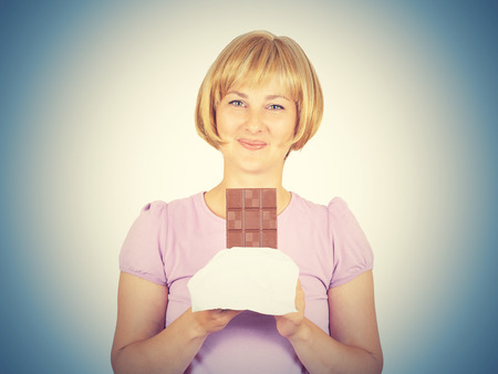 Portrait of young woman eat chocolate though. She exhausted diet. Greed sweet.  の写真素材