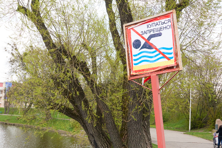 A sign to swim is forbidden on the shore of a lake in a city park in Russia. Text in Russian language.の写真素材