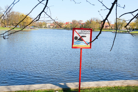 A sign to swim is forbidden on the shore of a lake in a city park in Russia. Text in Russian language.の写真素材