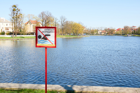 A sign to swim is forbidden on the shore of a lake in a city park in Russia. Text in Russian language.の写真素材