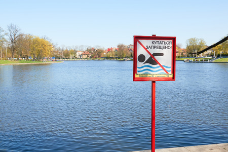 A sign to swim is forbidden on the shore of a lake in a city park in Russia. Text in Russian language.の写真素材